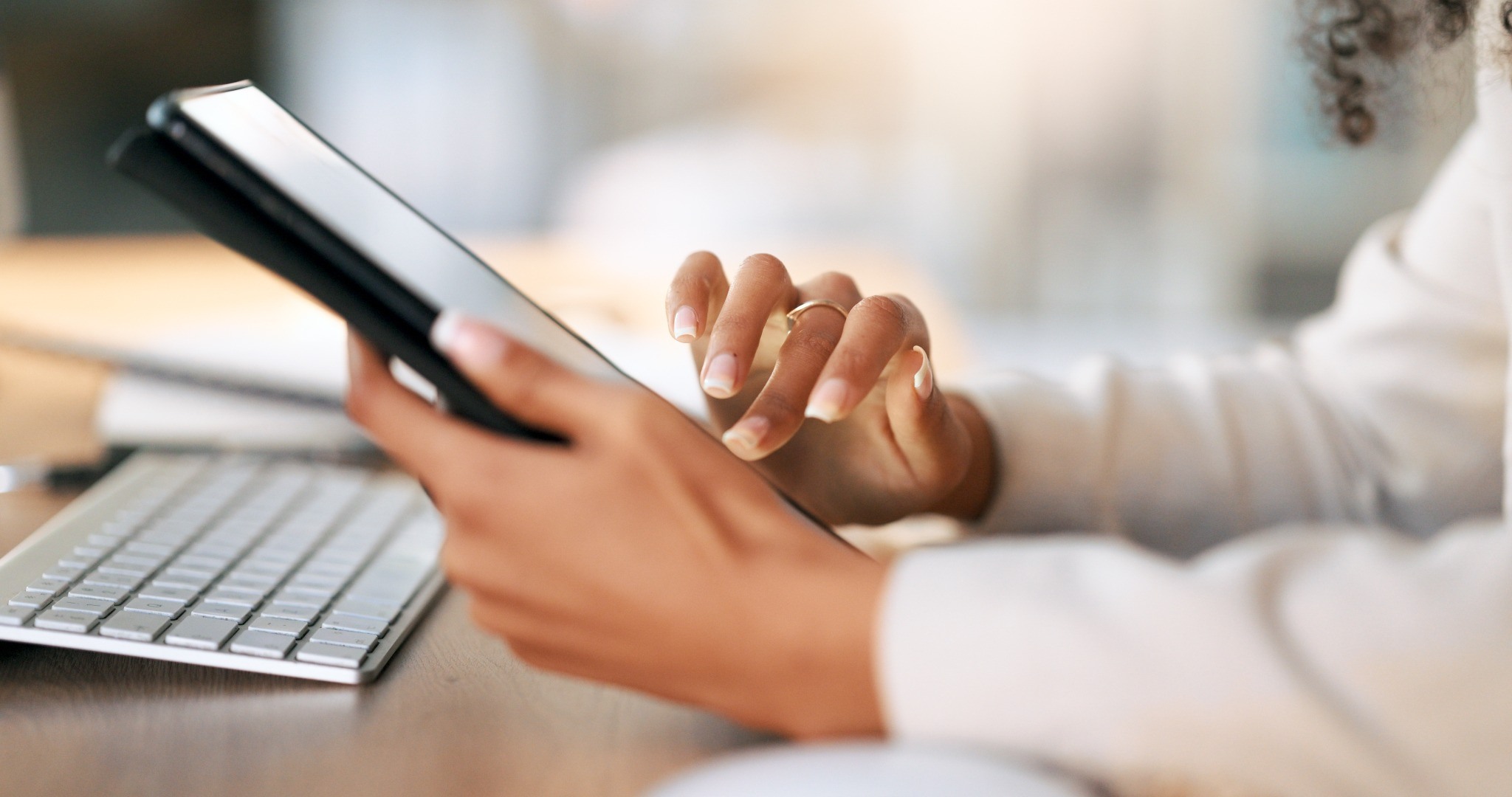 Person using a tablet beside a computer keyboard